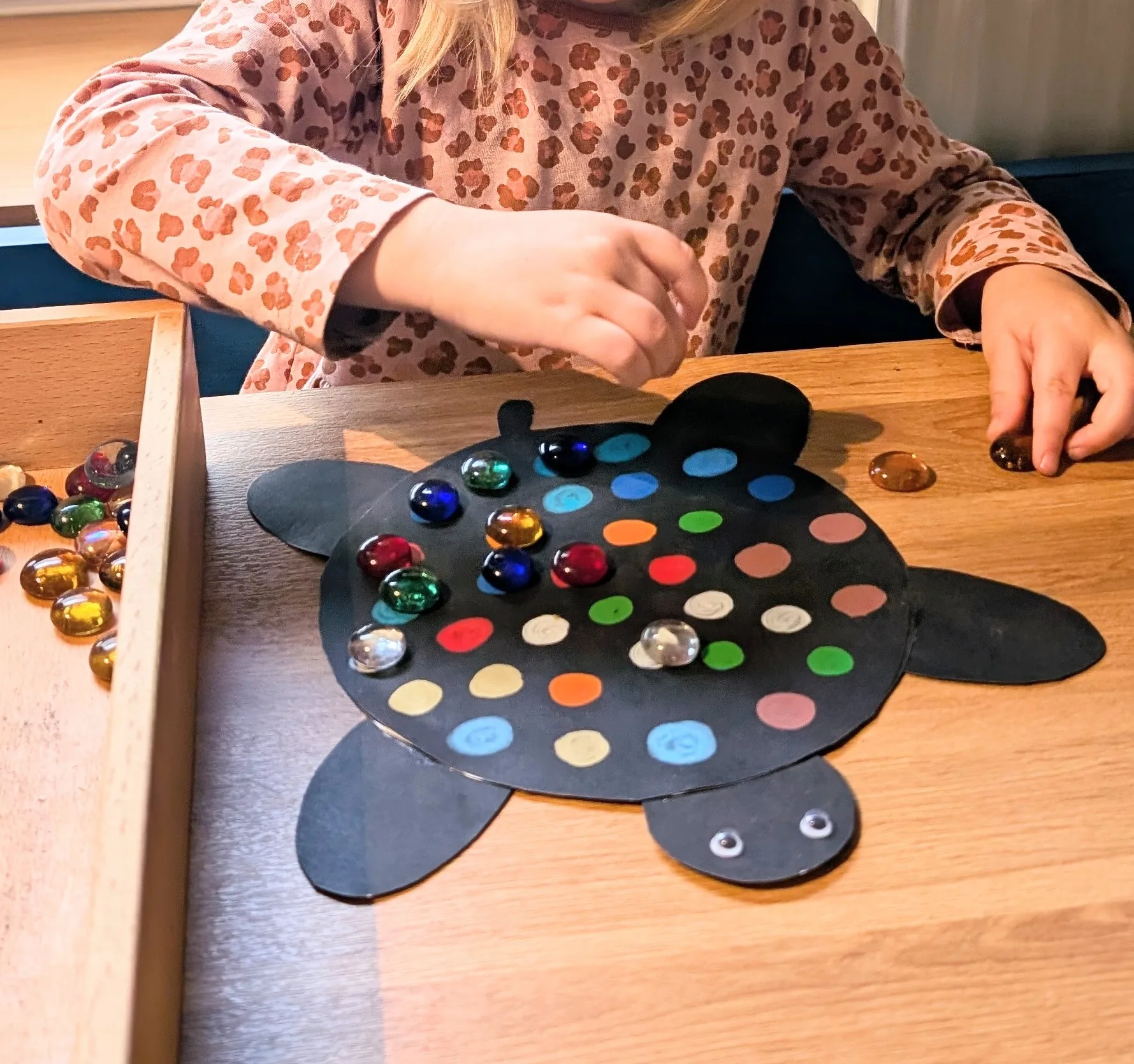 Kind spielt konzentriert mit bunten Glassteinen in der SandStube